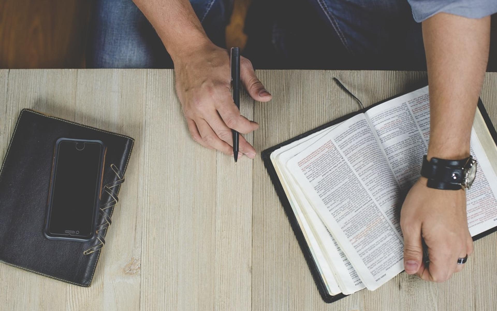 Mann mit Bibel und Smartphone (Symbolbild)