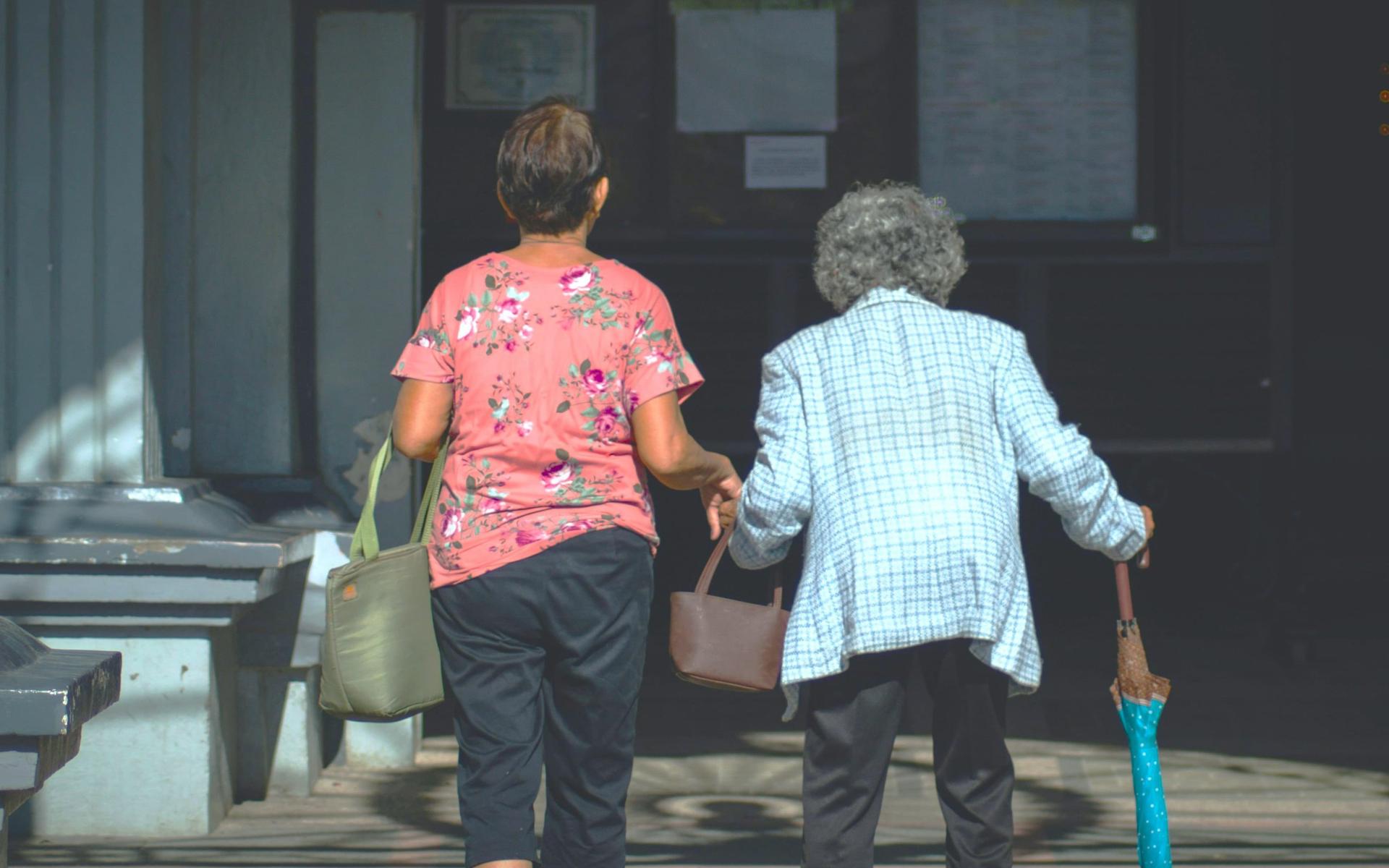 person-hilft-alter-frau-über-strasse