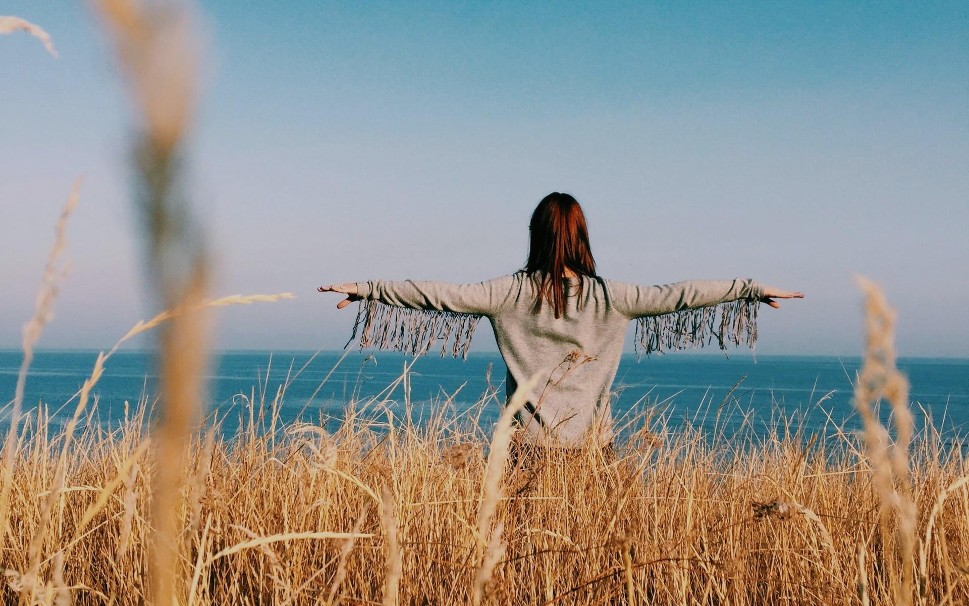 person-im-feld-vor-meer