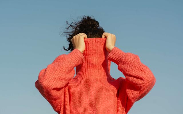 frau-zieht-sich-roten-pulli-ueber-das-gesicht