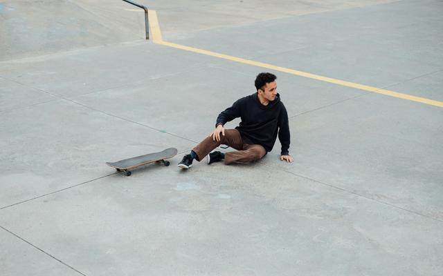 Mann der vom Skateboard gefallen ist