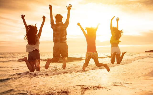 Gruppe begeisterter Freunde springt am Strand gleichzeitig in die Luft