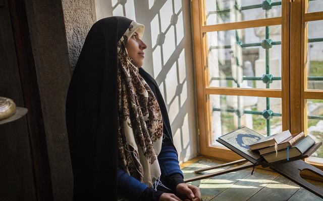 Verschleierte Frau sitzt am Fenster 