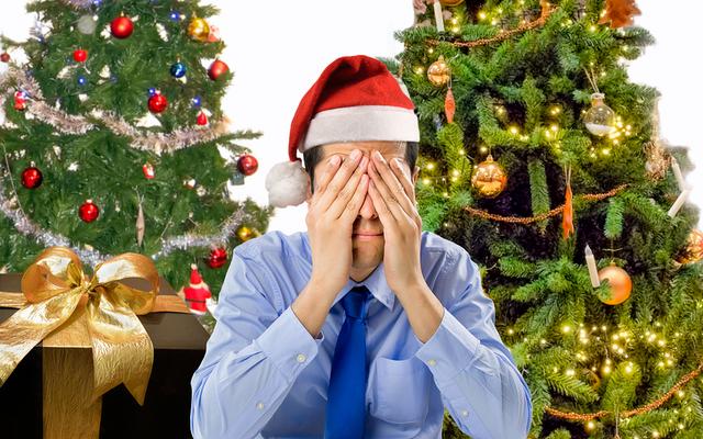 Gestresster Mann vor Weihnachtsbäumen