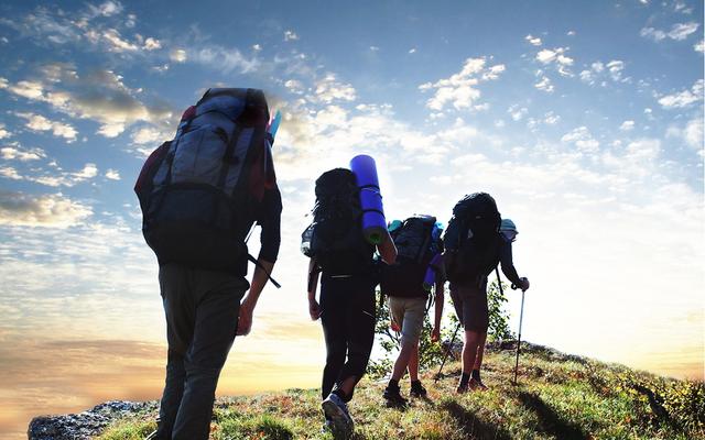 Wanderer laufen hintereinander auf einem Grat