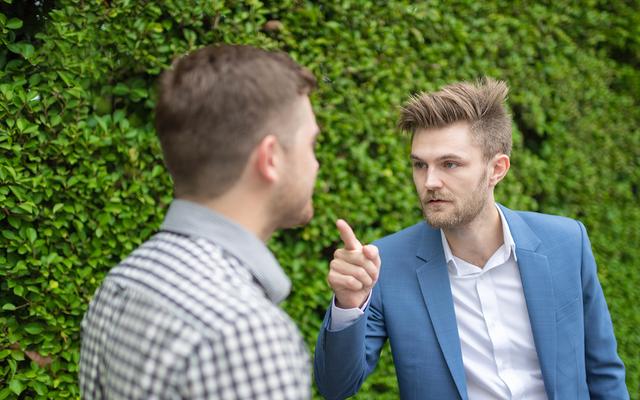 Mann zeigt mit dem Zeigefinger auf anderen Mann.