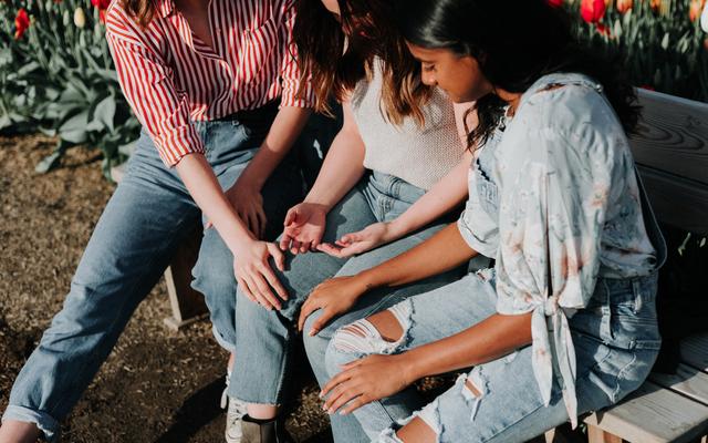 Drei junge Frauen beten miteinander