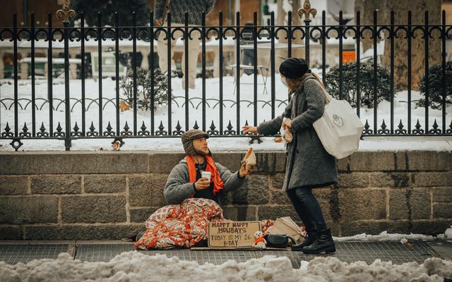 Frau hilft einem Obdachlosen