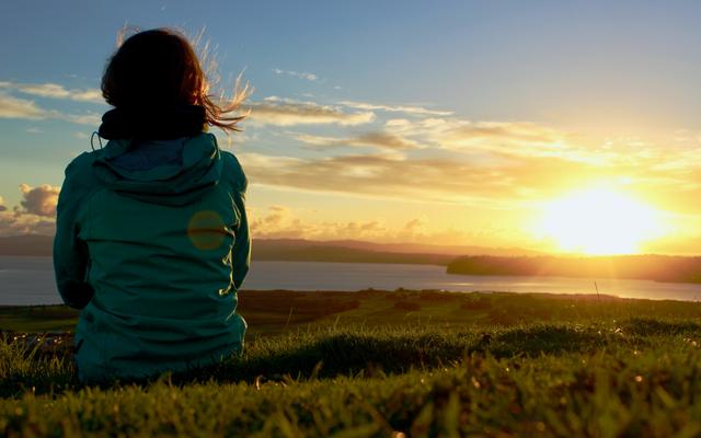 Eine Frau geniesst den Sonnenaufgang