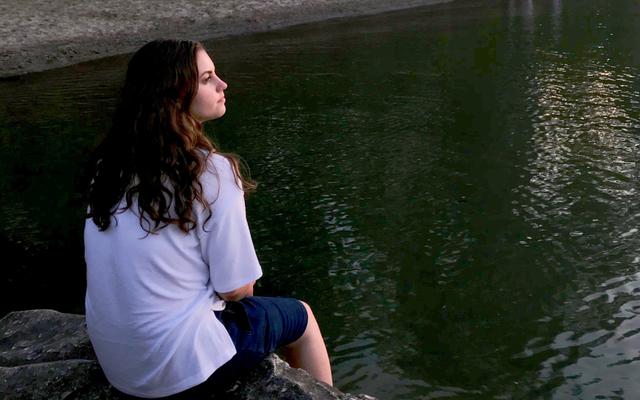 Junge Frau am See denkt nach