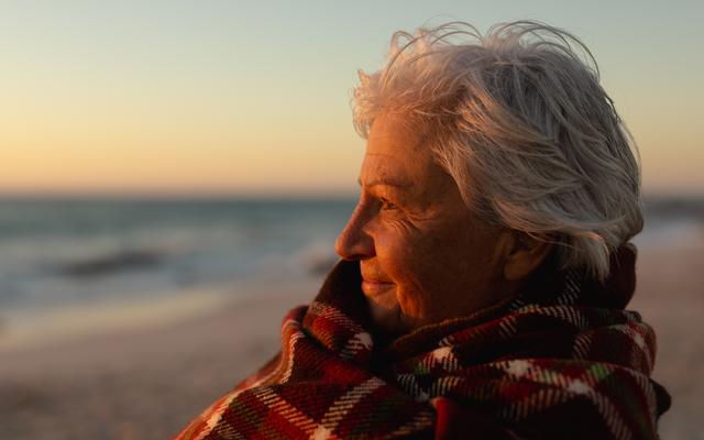Ältere Frau entspannt am Meer bei romantischer Abendstimmung