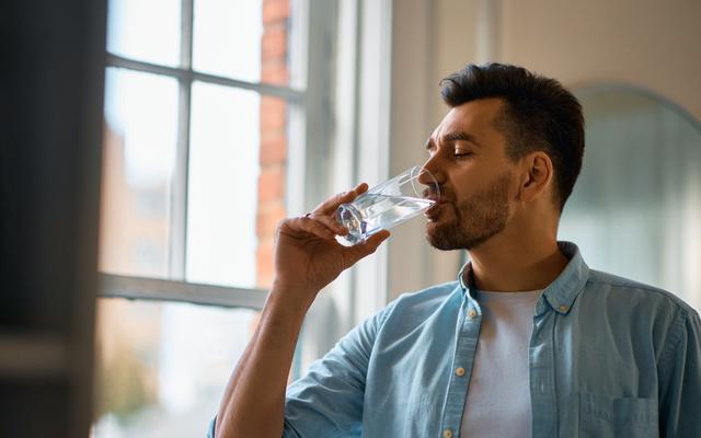 Durstiger Mann trinkt ein Glas Wasser
