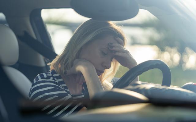 Frau sitzt verzweifelt im Auto