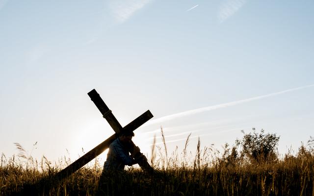 Mann trägt Kreuz auf dem Rücken