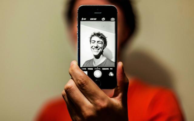 Junger Mann macht ein Selfie mit Graufilter. (Symbolbild)