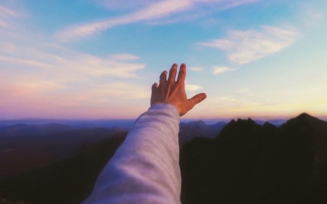 person-streckt-arm-in-den-himmel