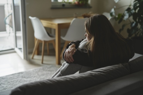 Frau sitzt alleine im Wohnzimmer
