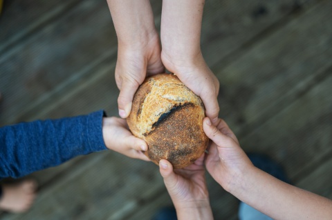 Mehrere Hände halten ein Brot