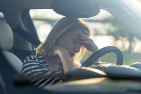 Frau sitzt verzweifelt im Auto
