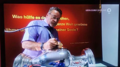 Der EM-Pokal wird graviert - ein Bibelvers im Hintergrund