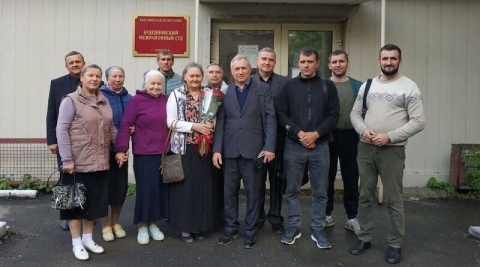 Vladimir Rudomyotkin (Mitte) und seine Frau Yelena (mit Blumen) sowei weiteren Gemeindemitgliedern vor dem Gerichtsgebäude in Donetsk