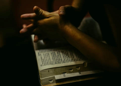 Betende Hände auf einer offenen Bibel