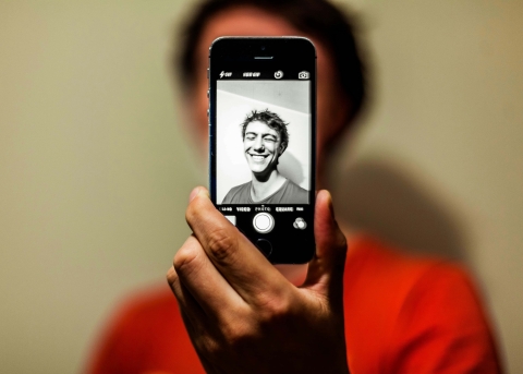 Junger Mann macht ein Selfie mit Graufilter. (Symbolbild)