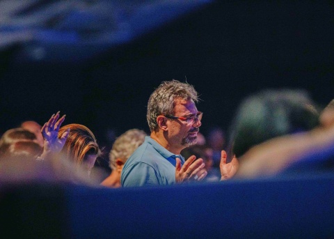 Älterer Mann im Gottesdienst mit jüngeren Menschen