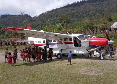 Kinder stehen neugierig um ein MAF-Flugzeug