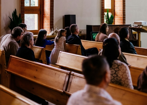 Eine Gruppe von Menschen, die in Kirchenbänken im Gottesdienst sitzen