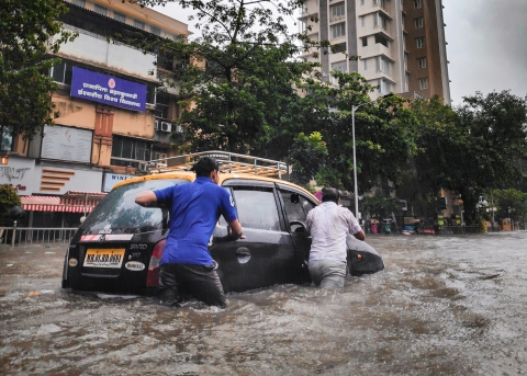 Menschen stehen knietief im Wasser auf einer überfluteten Strasse in Sri Lanka (Symbolbild)